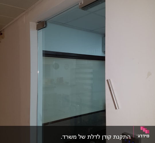 מערכת אינטרקום עם לוח מקשים ליד דלת זכוכית